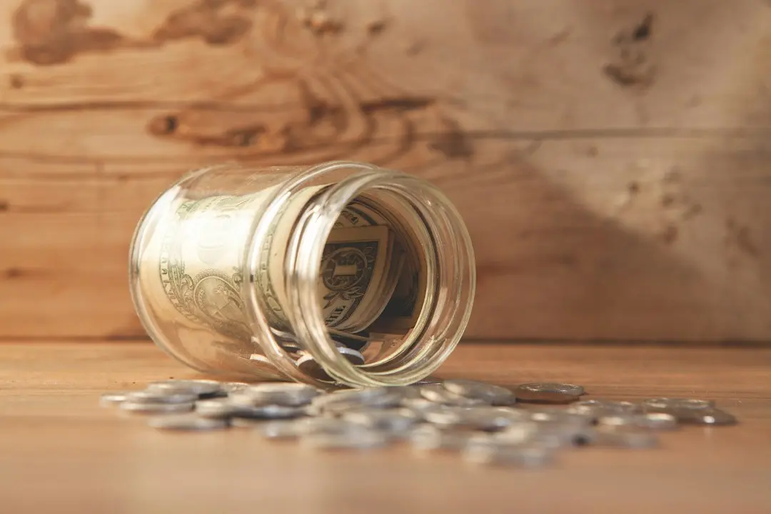 Un tarro de cristal con billetes y monedas sobre una mesa de madera, para calcular el ahorro con IPTV Fiesta
